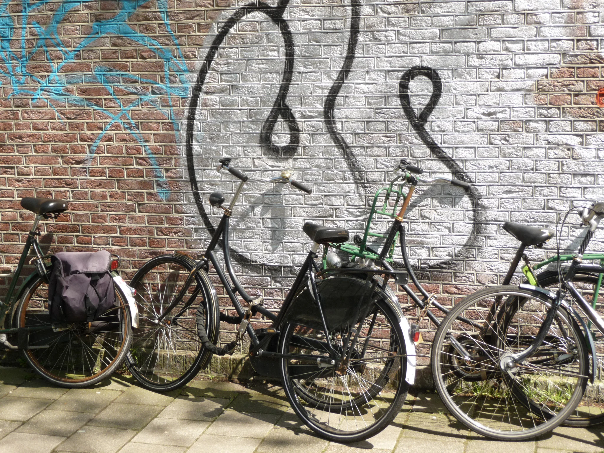 Bicycles parked against a graffiti-covered brick wall